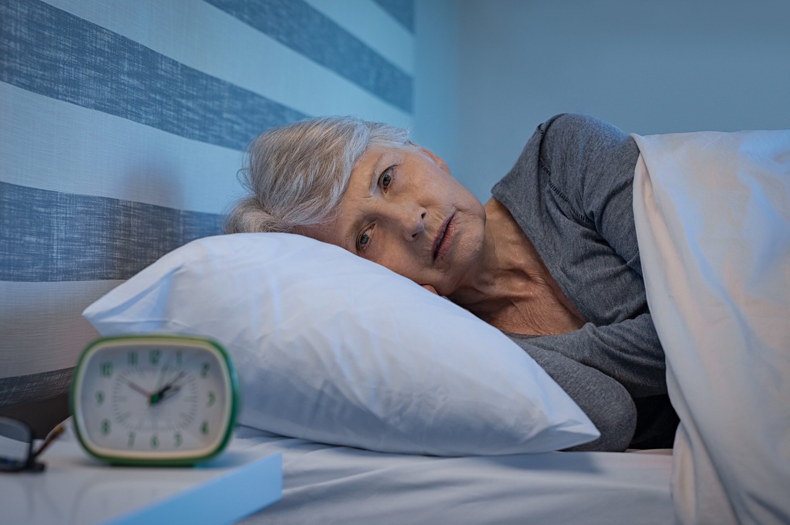 Worried senior woman in bed at night suffering from insomnia.